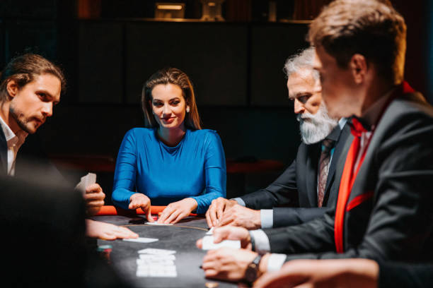 A group of male and female evening dress players sit at a gaming table with gaming chips. A group of male and female evening dress players sit at a gaming table with gaming chips. child gambling chip gambling poker stock pictures, royalty-free photos & images