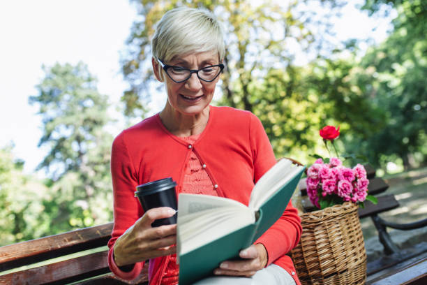 istock Retired woman reading a book on the bench 1397668876