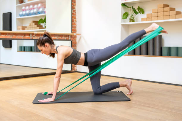 femme sportive faisant des exercices de yoga kick avec des bandes de résistance - glutes relaxation exercise muscular build human muscle photos et images de collection