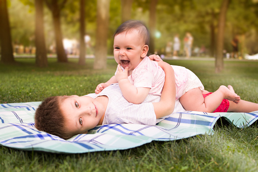 Hermano y hermana menor abrazados en una manta en el parque photo