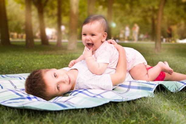 hermano y hermana menor abrazados en una manta en el parque - 6 11 meses fotografías e imágenes de stock