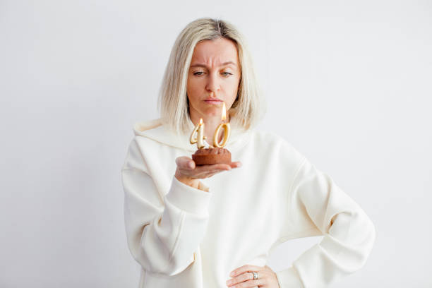 mujer hermosa adulta infeliz cuarenta años con cupcake festivo con vela - 40 44 years fotografías e imágenes de stock