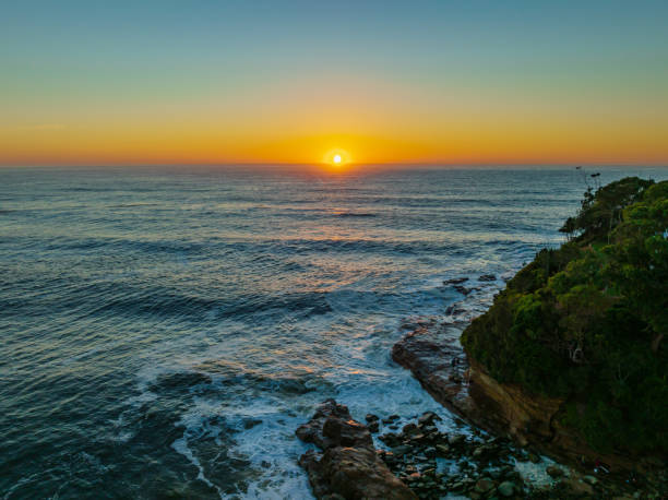 Clear skies aerial sunrise seascape Sunrise seascape with surfers and rocks at Avoca Beach on the Central Coast, NSW, Australia. avoca beach photos stock pictures, royalty-free photos & images