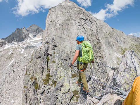 Wide angle view of sporty man climbing in summer on Via Ferrata in Switzerland