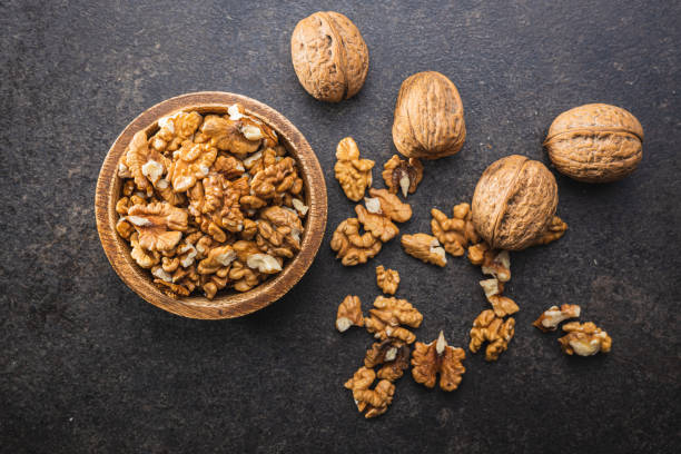 istock Peeled walnut kernels in wooden bowl on black table. 1397674910