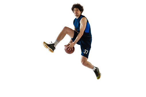 Low angle view of a young adult man scoring a goal in a basketball court. Sky in the background.