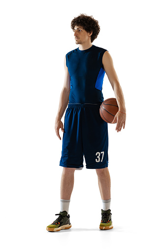 Full-length portrait of young muscular basketball player posing isolated on white background. Concept of sport, movement, energy and dynamic, healthy lifestyle. Copy space for ad