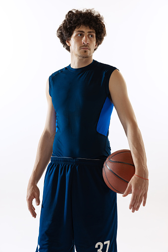 Looks concentrated. Portrait of young muscular basketball player posing isolated on white background. Concept of sport, movement, energy and dynamic, healthy lifestyle. Copy space for ad