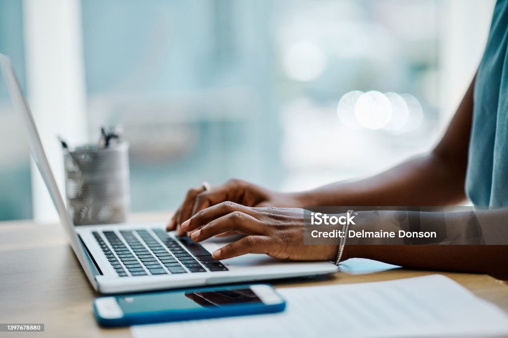 Closeup of a black businesswoman typing on a laptop keyboard in an office alone Laptop Stock Photo