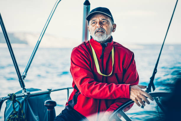 Confident skipper sailing on sailboat holding steering wheel.