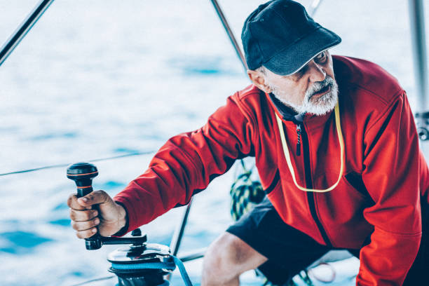 istock Skipper holding handle on winch of genoa sail on sailboat 1397678969