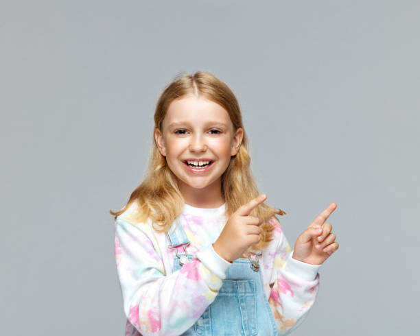 istock Happy girl pointing against gray background 1397679853
