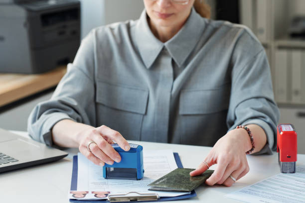 Putting Stamp Of Approval Selective focus shot of mature woman working as consular officer in embassy office sitting at desk putting seal on documents schengen agreement photos stock pictures, royalty-free photos & images