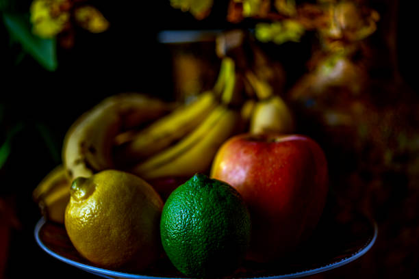 Dark still life of fruit on a plate with black background