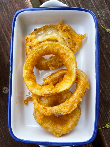 Stock photo showing elevated view of white dish of beer-battered onion rings.