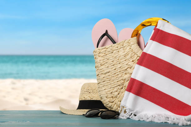 Beach bag with towel, flip flops, hat and sunglasses on light blue wooden surface near seashore. Space for text Beach bag with towel, flip flops, hat and sunglasses on light blue wooden surface near seashore. Space for text beach bag stock pictures, royalty-free photos & images