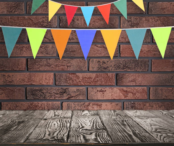 istock Empty wooden table and decorative bunting flags hanging on brick wall 1397685067