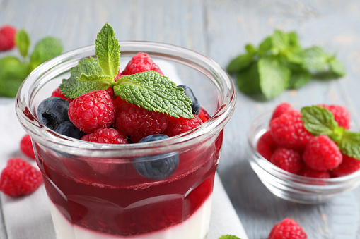 Delicious panna cotta with berries in glass dish, closeup