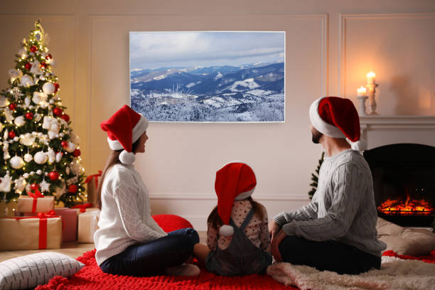 크리스마스를 위해 장식 된 방에서 tv를 보는 가족 - blanket fireplace winter women 뉴스 사진 이미지