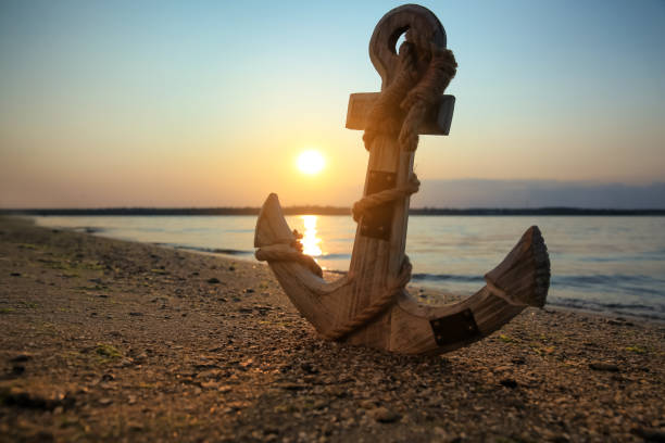 istock Wooden anchor on shore near river at sunset 1397685370