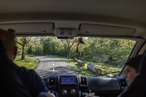 Young man driving his camper van down a leafy mountain road with his accompanying son