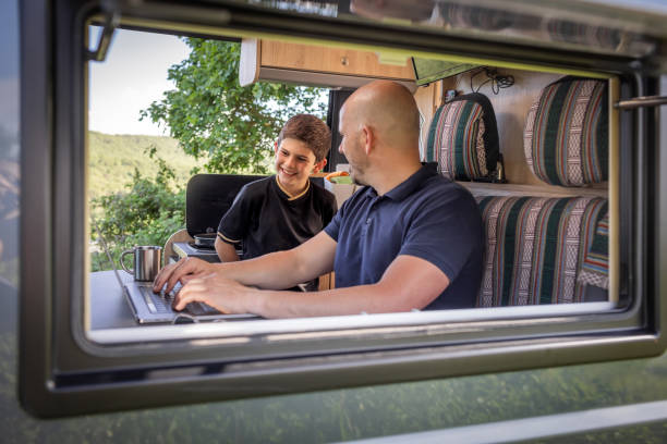 자연에서 캠핑카 밴에서 노트북을 작업하고 아들이 웃고있는 화면을 보는 동안 집중된 남자 - class a motorhome 뉴스 사진 이미지