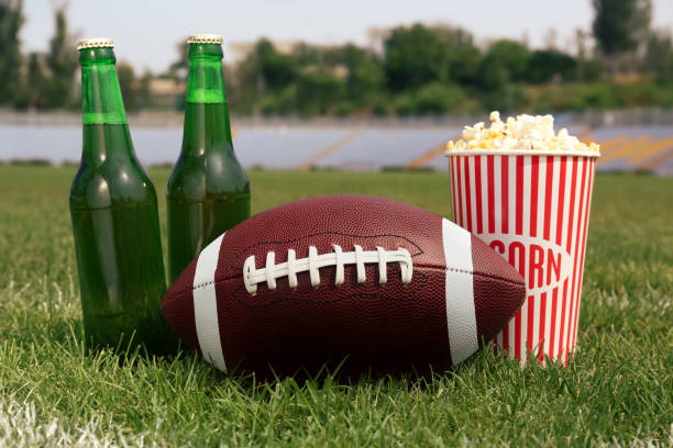 american football ball with beer and popcorn on green field grass in stadium - junior high fotos imagens e fotografias de stock