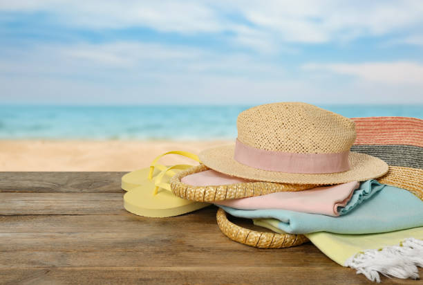 istock Beach bag with towel, hat and flip flops on wooden surface near seashore. Space for text 1397689712