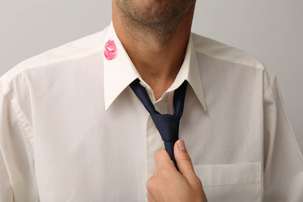 woman grabbing her husband by tie due lipstick kiss mark on his shirt, closeup - proof of love imagens e fotografias de stock