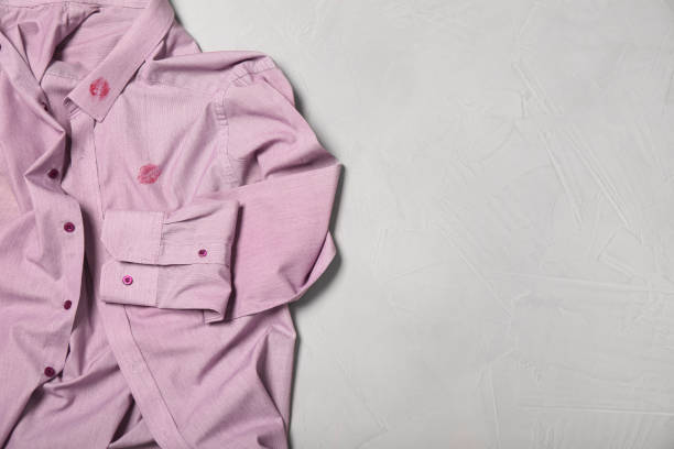 istock Men's shirt with lipstick kiss marks on light background, top view. Space for text 1397689833
