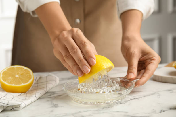 istock Woman squeezing lemon juice at white marble table, closeup 1397689869