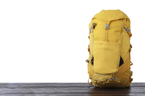 Hiking backpack on wooden surface against white background. Space for text