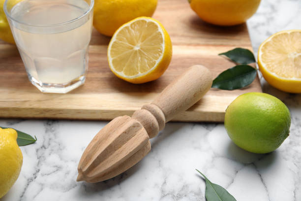istock Wooden citrus reamer, fresh lemons and lime on white marble table 1397690892