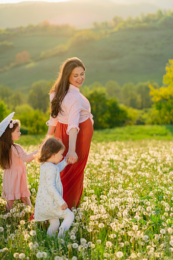 Pregnant mother with daughters in the nature