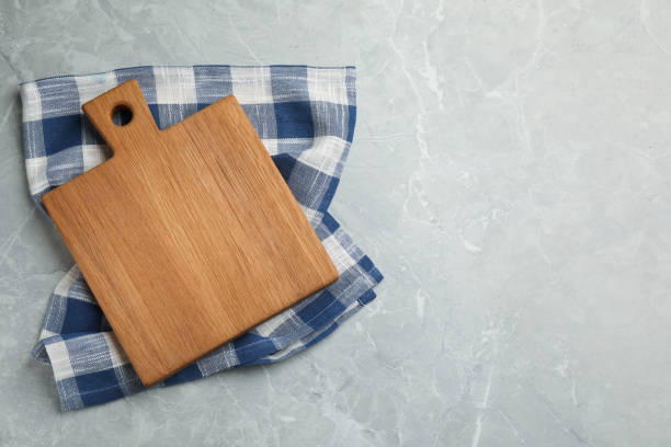 istock Kitchen towel and wooden cutting board on grey table, top view. Space for text 1397691337