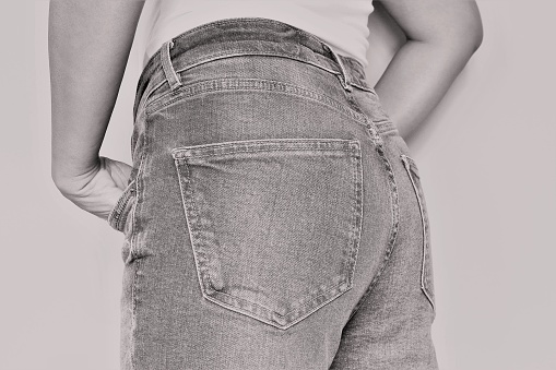 backside of woman part wearing jean trousers. photo back and white color