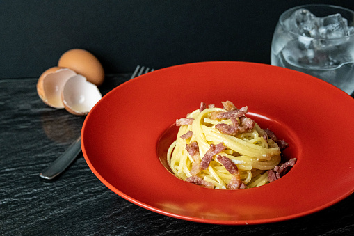 A portion of Original Italian Carbonara, traditional food birth in the region of Lazio: Onion, fried bacon, parmesan and eggs.