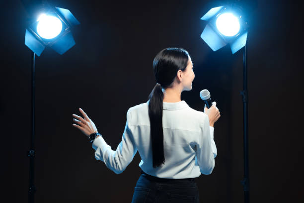 Motivational speaker with microphone performing on stage, back view