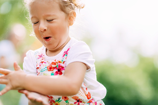 A happy laughing baby is running around the park or garden. Summer, summer time, happy days.