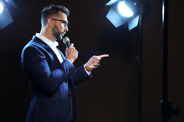 istock Motivational speaker with microphone performing on stage. Space for text 1397696355