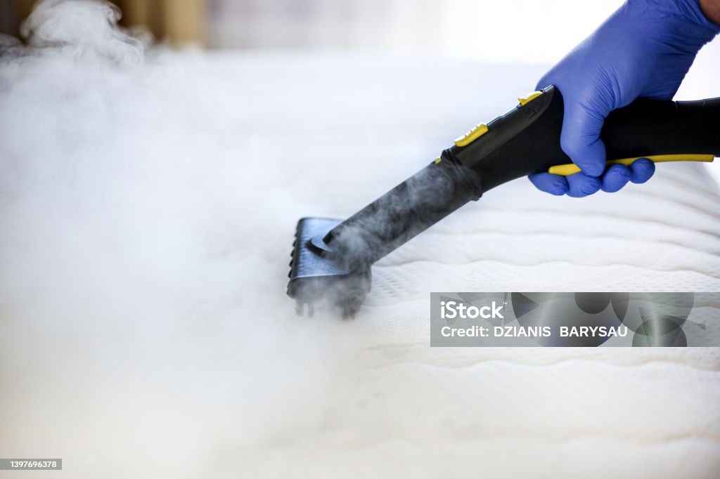 Cleaning and disinfection of the mattress in the bedroom with hot steam. Professional cleaning process Mattress Stock Photo