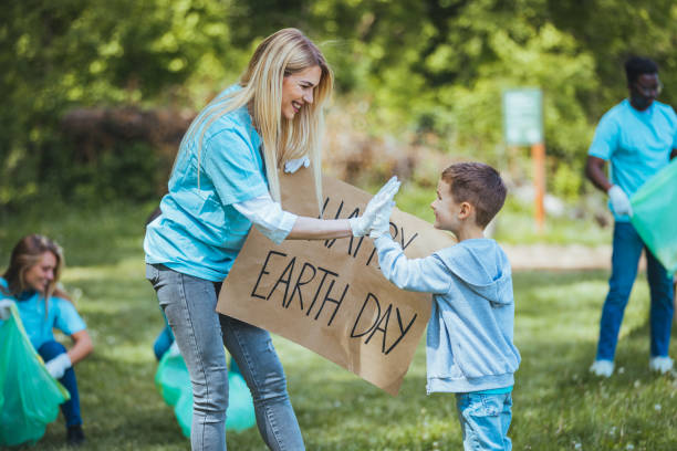 happy volunteers holding placard with 'happy earth day' message. - earth globe mother child imagens e fotografias de stock