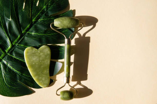 istock Jade Gua sha scraper and face roller massager on a cork round stand with a monstera leaf. 1397697184