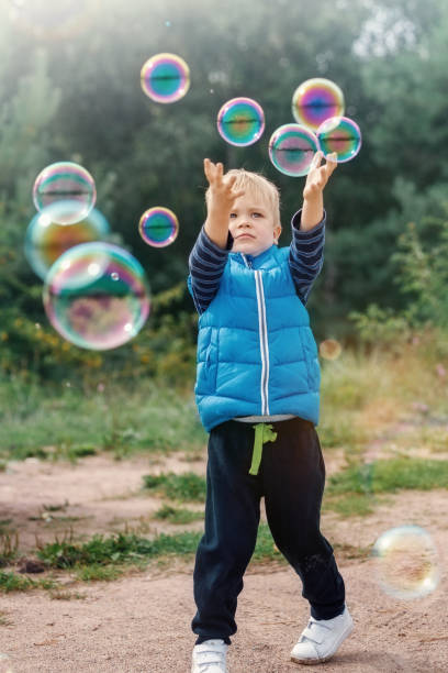 istock The little boy catches soap bubbles in autumn nature. 1397697485