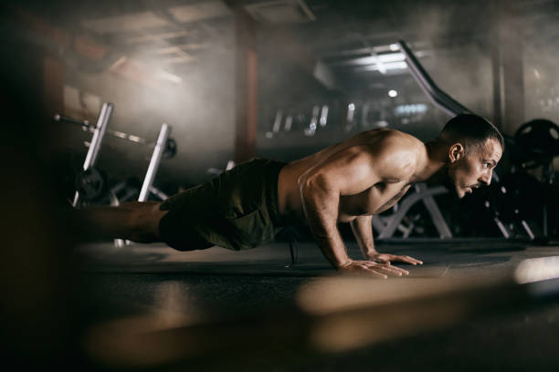 muscular build men exercising push-ups in a gym. - exercising men push ups muscular build imagens e fotografias de stock