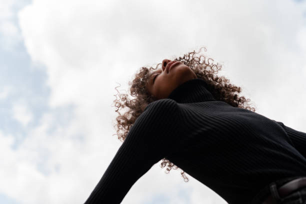 istock Young african american woman posing against clouds background 1397699035