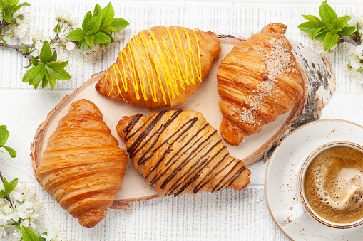 Various croissants and coffee cup on wooden board. French breakfast. Top view flat lay