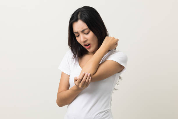 Asian woman has problem with structural posture She has elbow hurts. She massaged for relief. reduce muscle tension. Standing on isolated white background Asian woman has problem with structural posture She has elbow hurts. She massaged for relief. reduce muscle tension. Standing on isolated white background muscle and joint pain relief stock pictures, royalty-free photos & images