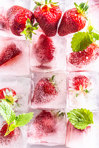 Three rows of ice cubes with strawberries with mellisa leaves - Top of view.