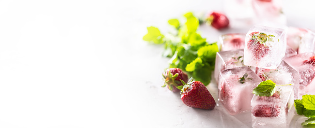 Strawberries frozen in ice cubes with melissa leaves, banner with copy cpace.